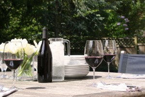 An outdoor table set with plates and red wine